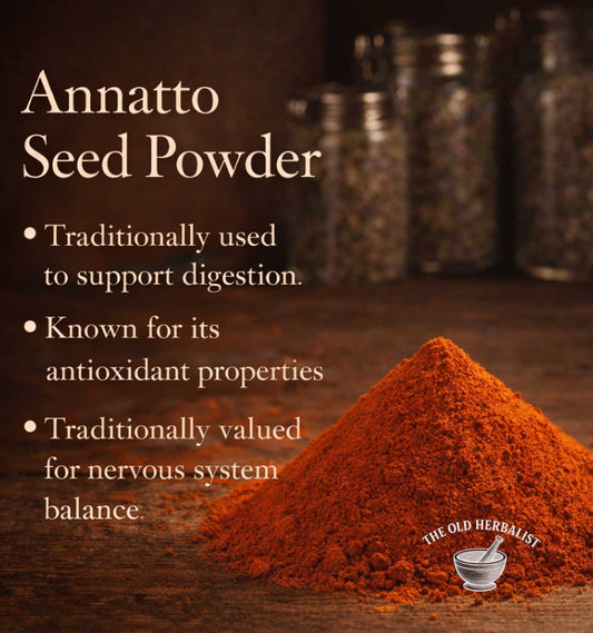 Annatto seed powder with text about its uses on a wooden surface, featuring The Old Herbalist logo.