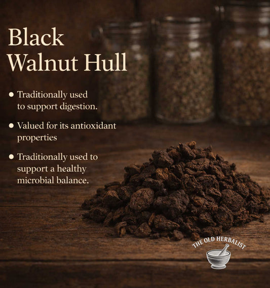 Black walnut hulls on a wooden surface with text about its uses and The Old Herbalist branding.