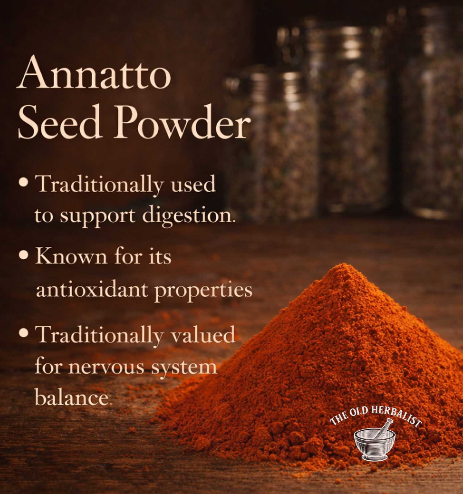 Annatto seed powder with text about its uses on a wooden surface, featuring The Old Herbalist logo.
