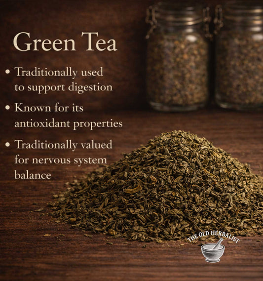 Green tea leaves on a wooden surface with text about its benefits and The Old Herbalist logo.